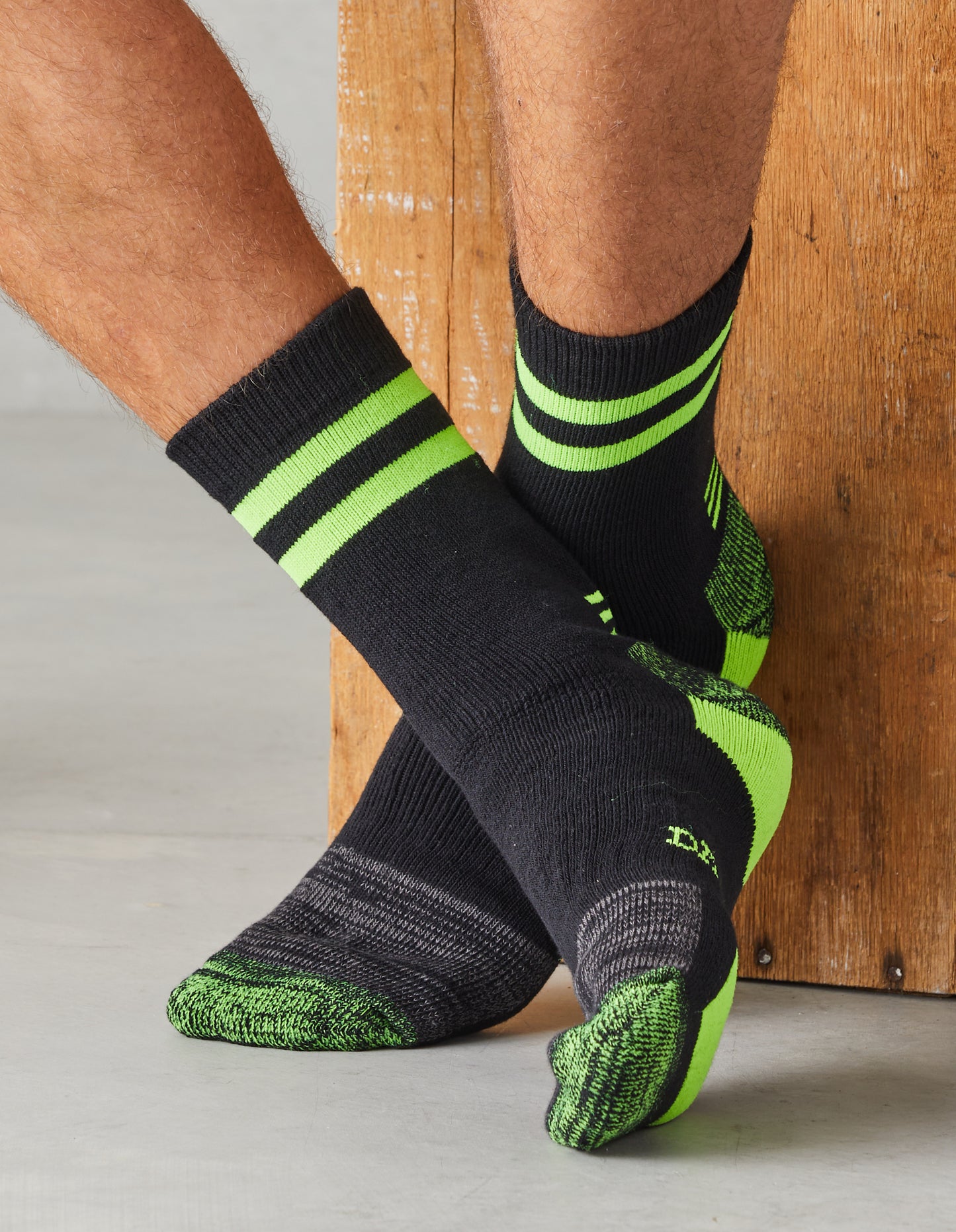 Man wearing Darn Tough Men's Steel Cap Work Socks in Green, crossing ankles