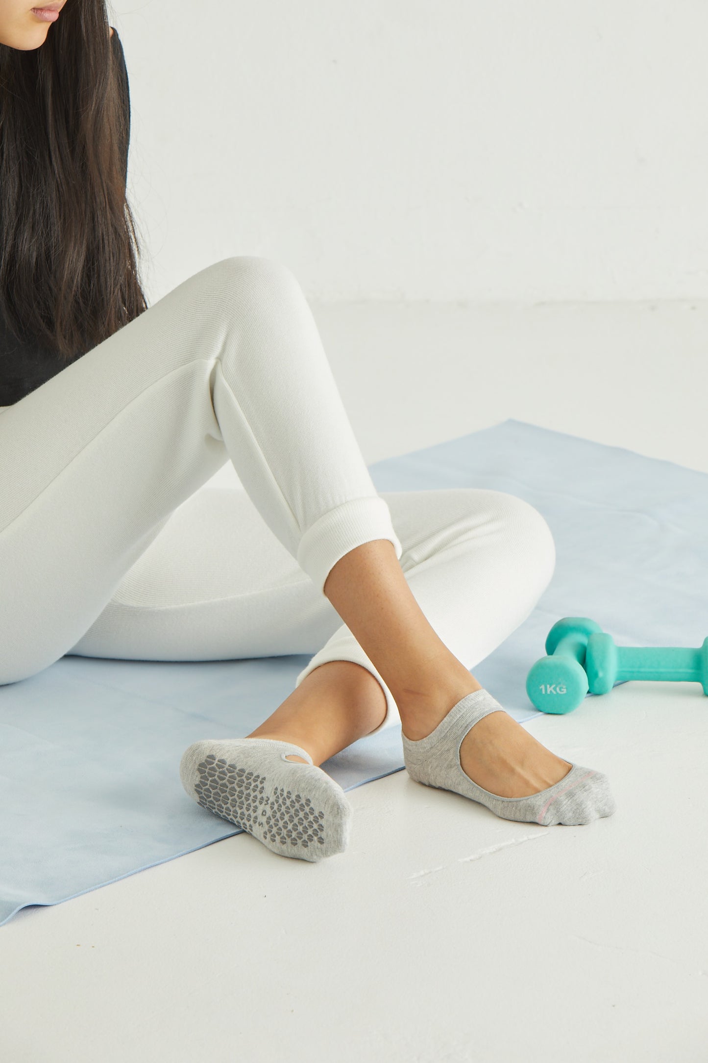 Woman wearing Simon de Winter Women's Cotton Yoga Socks in Light Grey Marle while sitting on yoga mat
