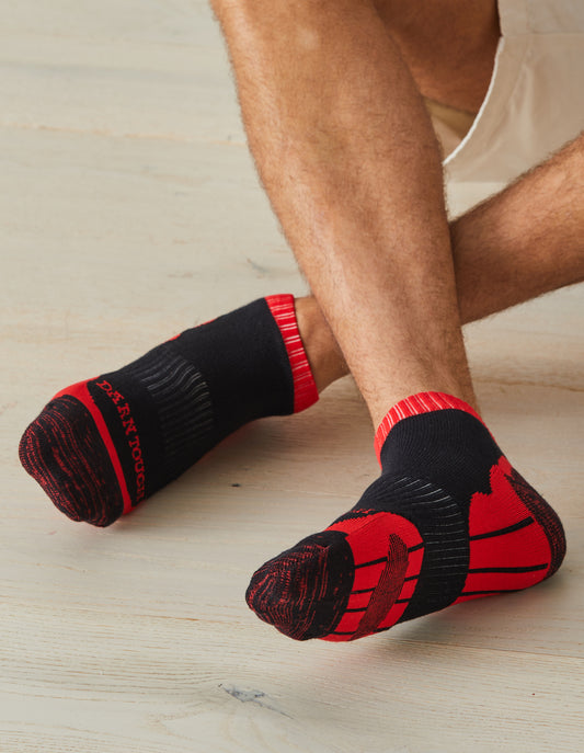 Man wearing Darn Tough Men's Sports Ankle Socks in red with ankles crossed