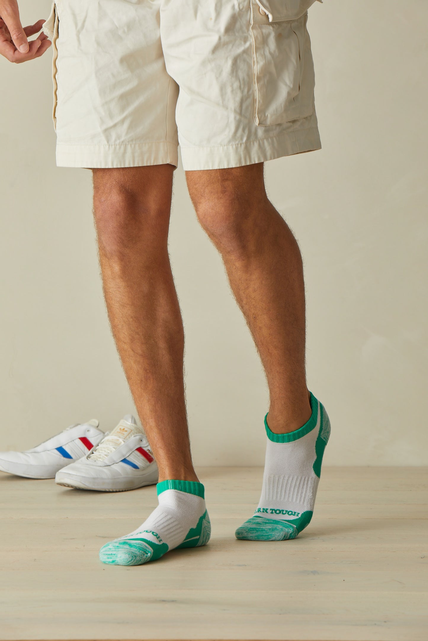 Man standing wearing Darn Tough Men's Sports Ankle Socks in Green
